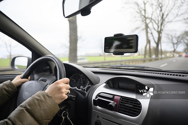 女人手握方向盘在乡村道路上行驶的细节图片素材