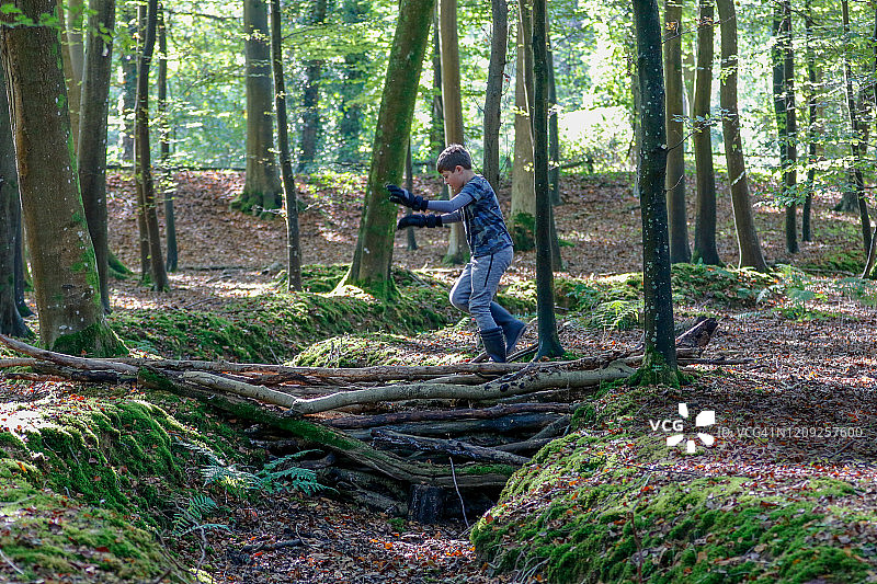 男孩穿过树林里的临时桥梁图片素材
