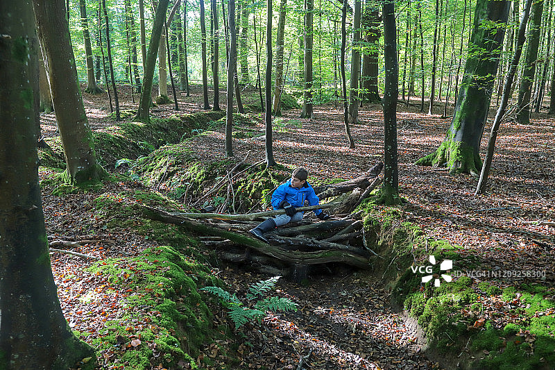 男孩在森林里搭建简易桥梁图片素材