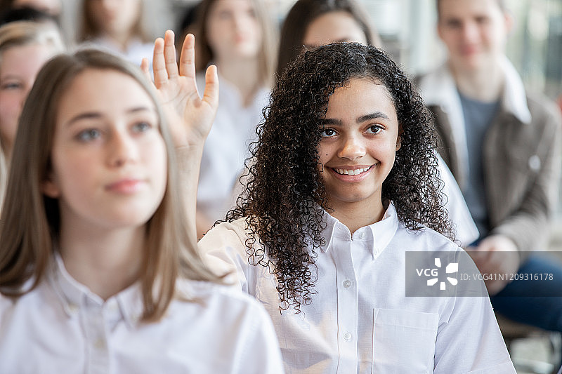 私立学校的青少年学生在课堂上举手提问图片素材