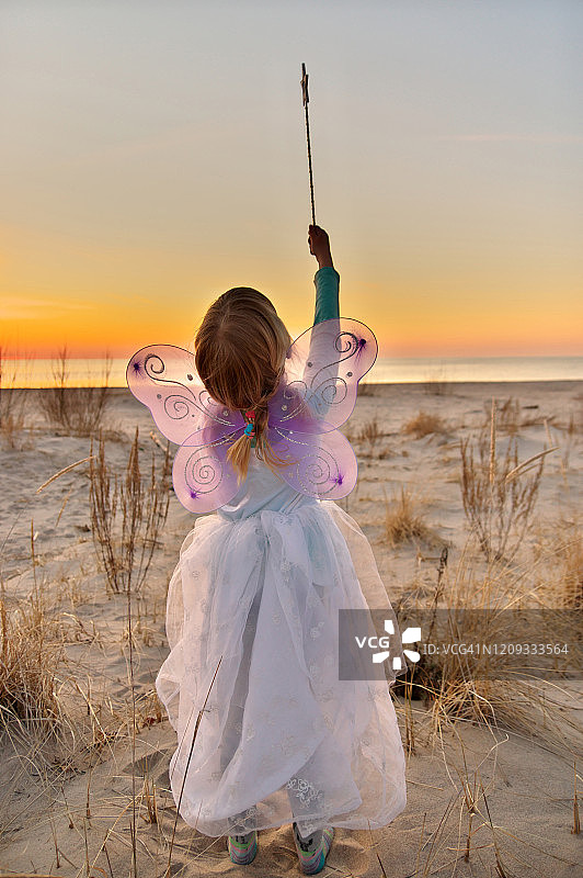 装扮成仙女指向天空的年轻女孩的抓拍肖像—后视图图片素材