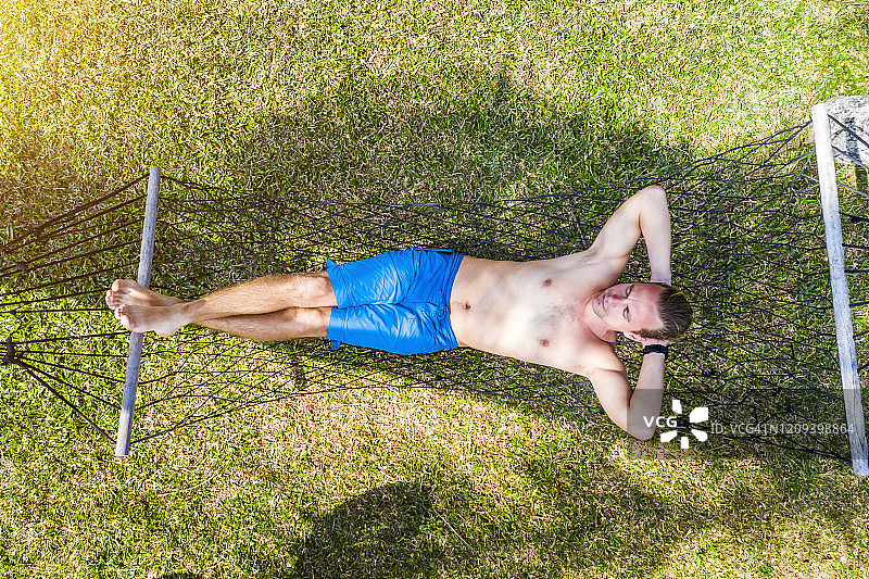 年轻男人在热带海滩的吊床上放松图片素材