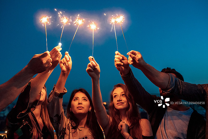 人们手持烟花棒，以天空为背景图片素材