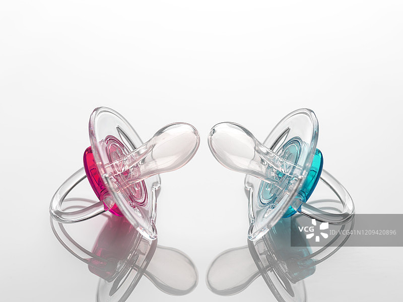 粉色和蓝色婴儿奶嘴，象征性别不平等图片素材