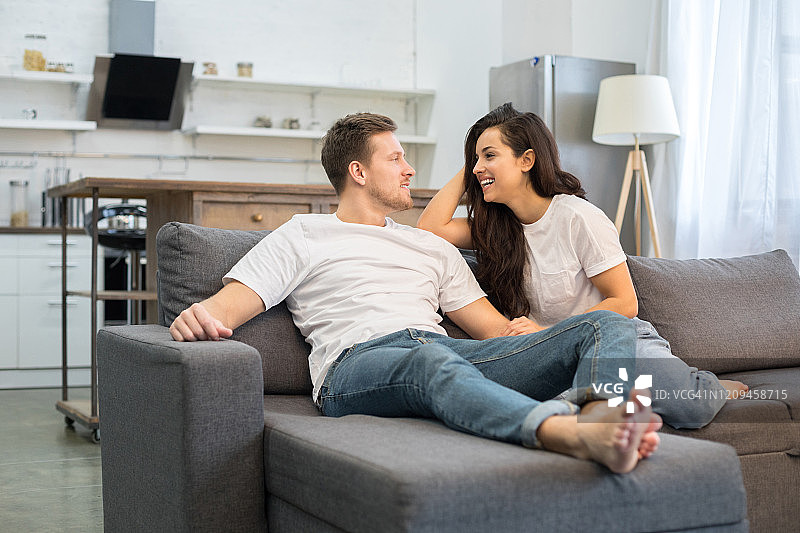 快乐的年轻男人在家与漂亮的女人交谈图片素材