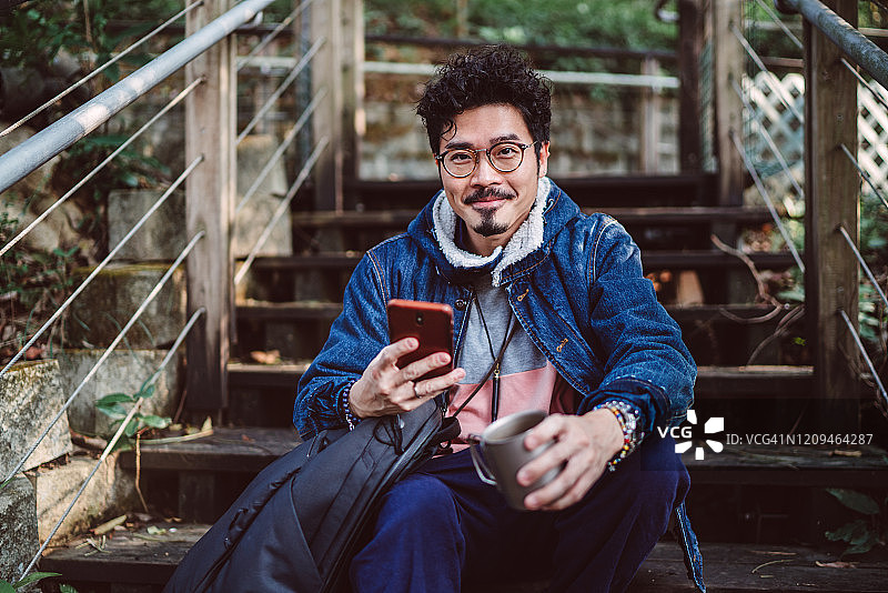 在乡村使用智能手机的年轻亚洲男人图片素材