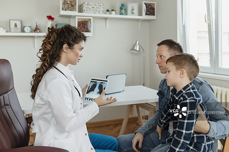 医生在平板电脑上向父亲展示医疗结果图片素材