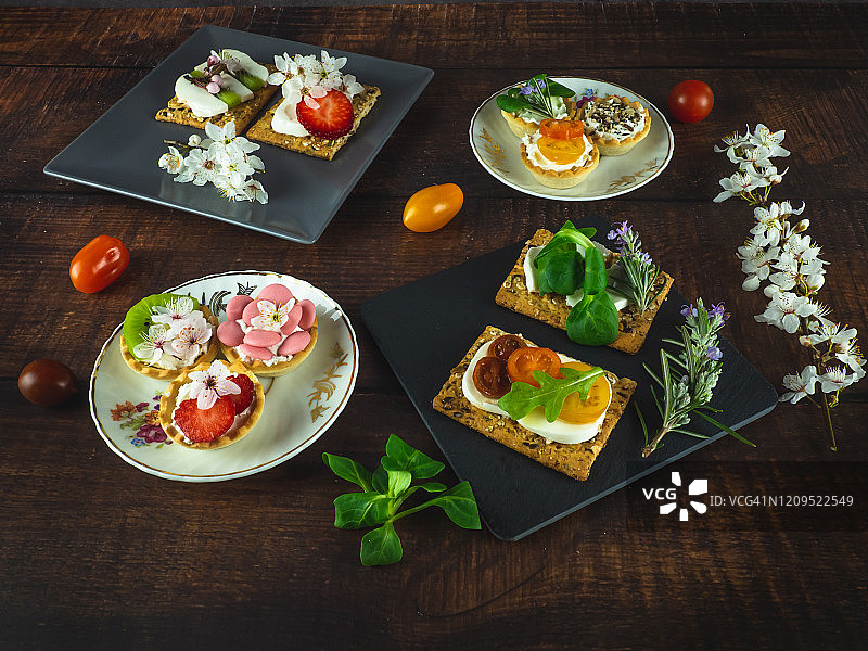 木桌上带有鲜花和樱桃番茄的甜咸小吃图片素材