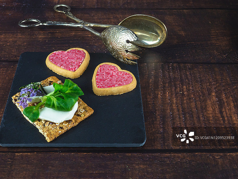 甜味小餐点，配新鲜奶酪、猕猴桃、食用花卉、心形饼干和复古羊驼上菜钳图片素材