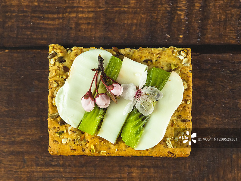 自制小点心：斯佩尔特饼干和奶酪、新鲜奶酪、猕猴桃和食用花图片素材