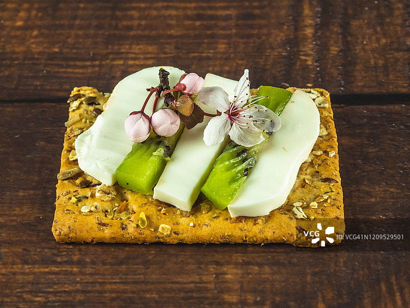 自制小点心：斯佩尔特饼干和奶酪、新鲜奶酪、猕猴桃和食用花图片素材