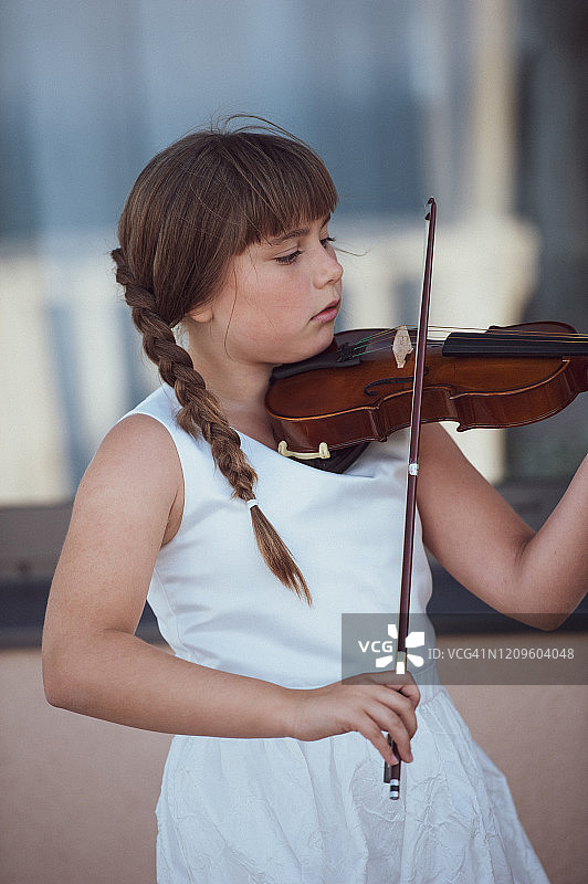 在仪式上拉小提琴的白色连衣裙可爱女孩图片素材