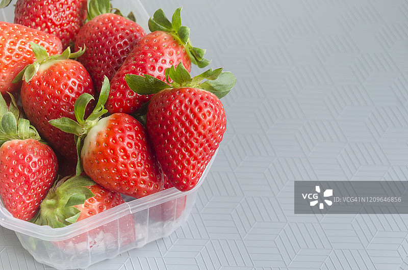 灰色背景塑料容器中的新鲜草莓图片素材