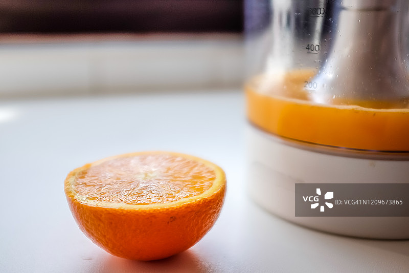 榨汁机旁的半个橙子和橙汁图片素材