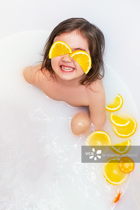 女婴用橘子洗牛奶浴。图片素材