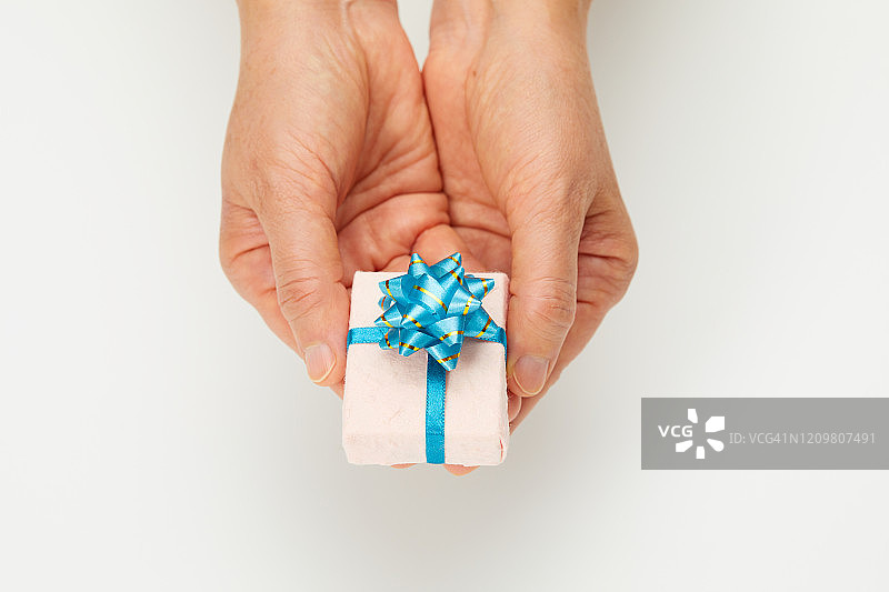 双手捧着白色背景上的蓝色丝带礼品图片素材