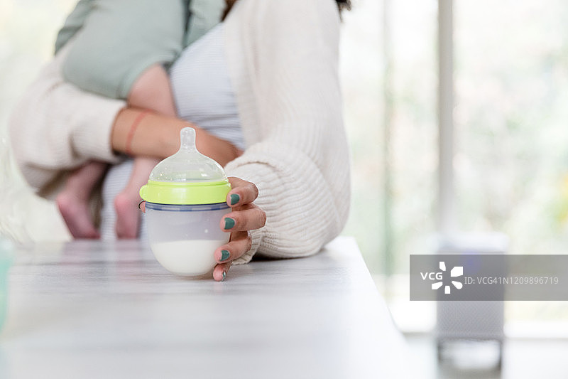 女人拿起婴儿奶瓶图片素材