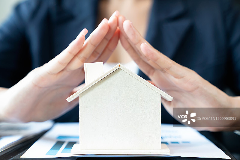 女商人覆盖木制房屋。财产保险和安全概念图片素材