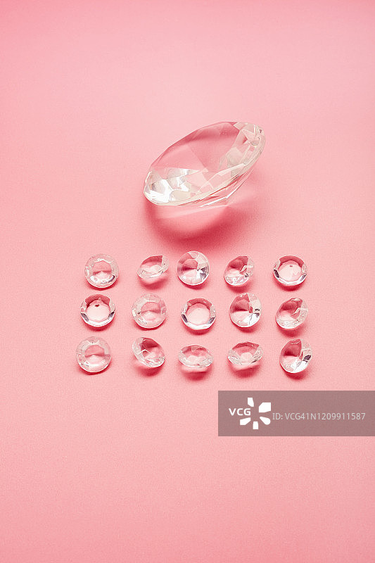 粉色背景上的大颗和多颗小颗仿制钻石高角度视图图片素材