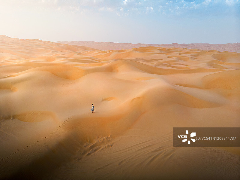 女人走在沙漠沙丘上的航拍图图片素材