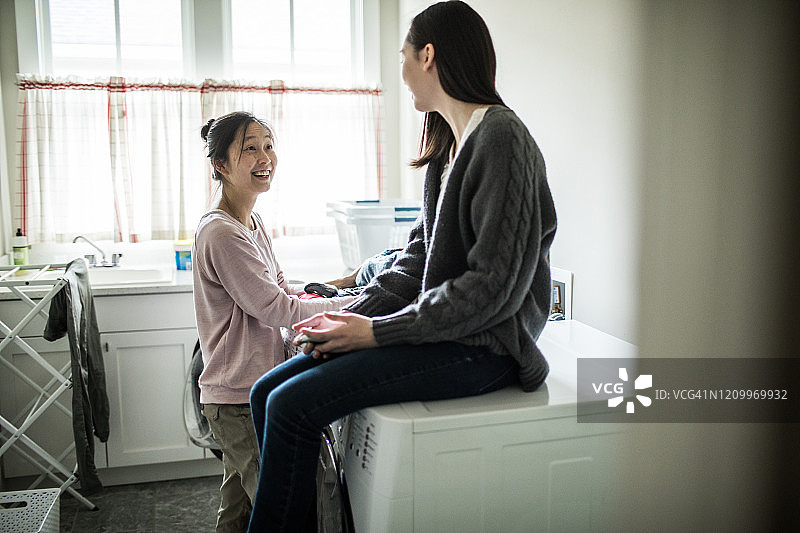 少女在洗衣房和母亲聊天图片素材