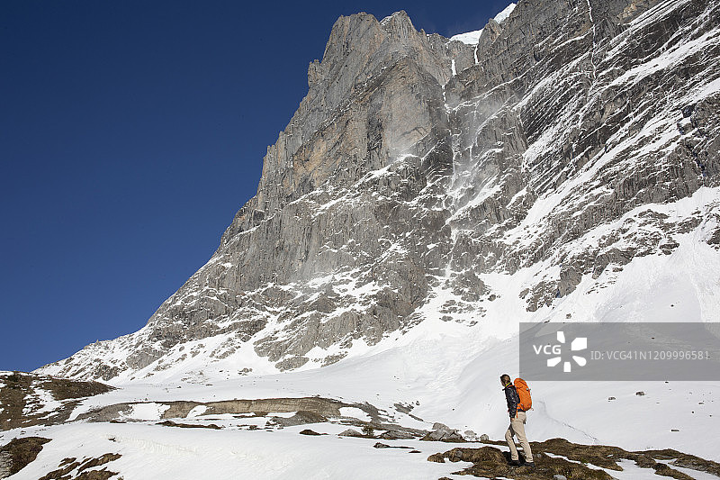 在山中攀登雪坡的男性徒步者图片素材