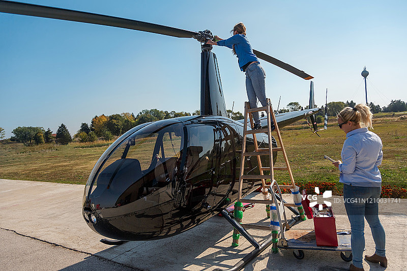 在梯子上清洁直升机旋翼的年轻女人图片素材