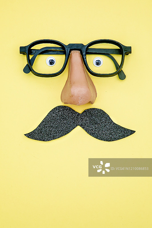 带假胡子和滑稽眼睛的新奇眼镜，黄色背景图片素材