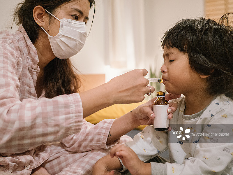 生病的小男孩从母亲那里服用药物糖浆图片素材