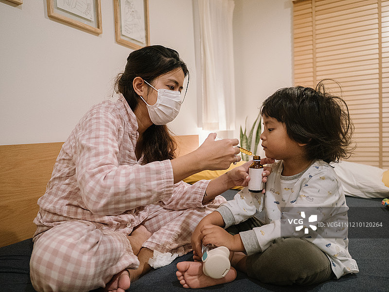 生病的小男孩从母亲那里服用药物糖浆图片素材