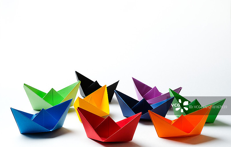 白色背景上的明亮彩色纸船，留白图片素材