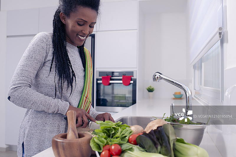 快乐的女人在厨房台面上准备沙拉图片素材
