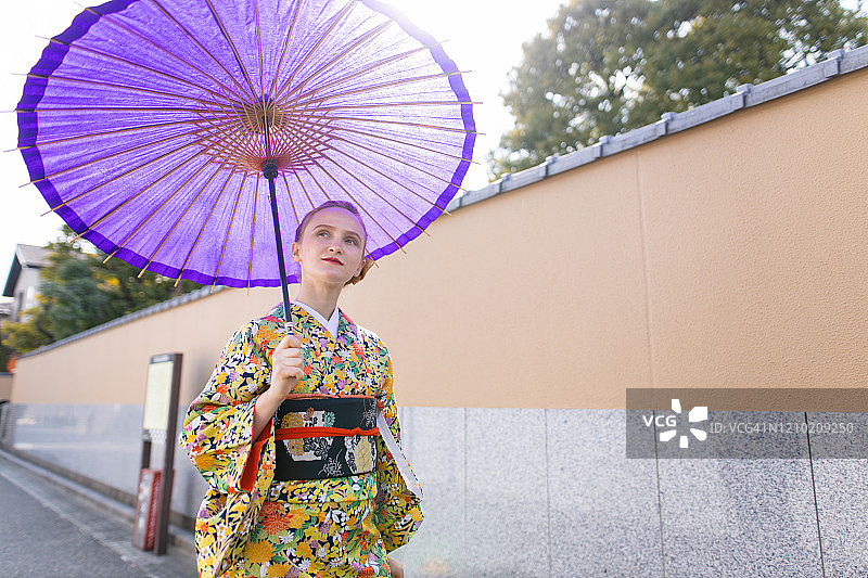 穿着和服的年轻白人女性走在日本传统街道上。图片素材