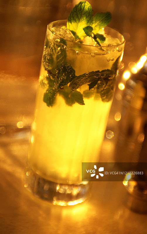 莫吉托鸡尾酒加柠檬和压碎的薄荷叶-在晚上戏剧性地点燃图片素材