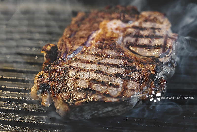 在烤盘上烹饪的牛排，滋滋作响的肉图片素材