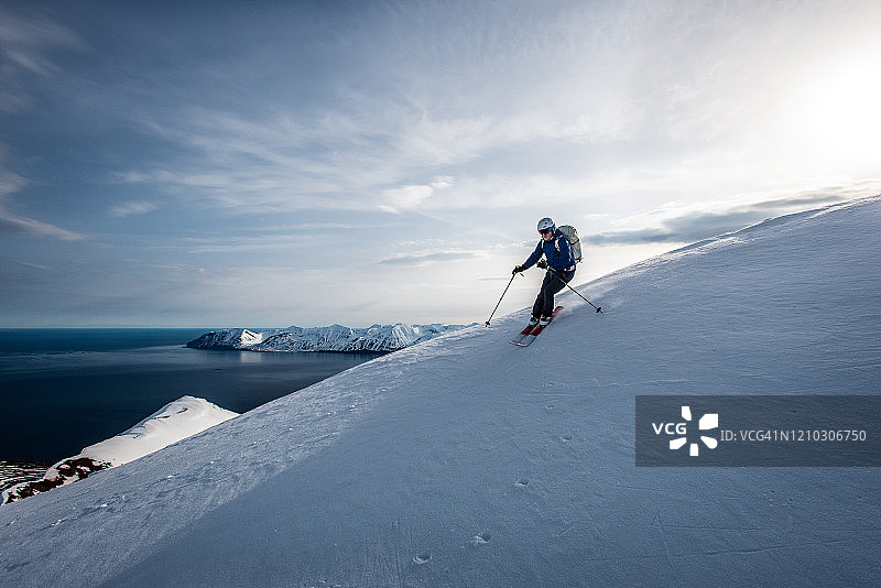 一名男子在冰岛滑雪下坡，背景是海洋图片素材