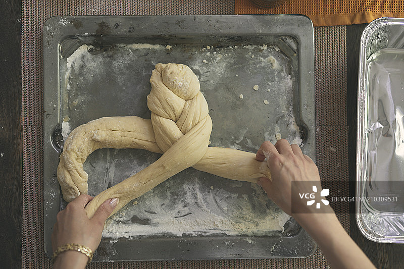 在桌旁编织 challah 面包的手部照片图片素材
