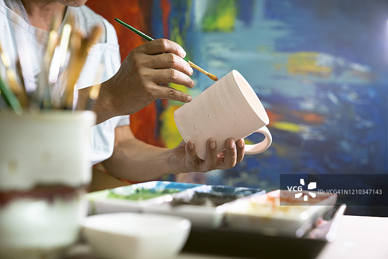 男子在小型工艺品工作室里绘画杯子的特写镜头图片素材