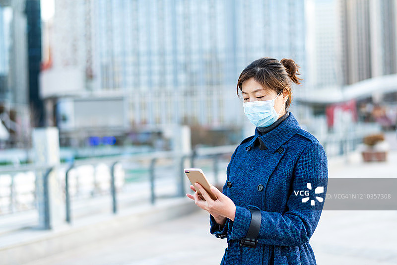 戴口罩的亚洲女人走在城市街道上图片素材
