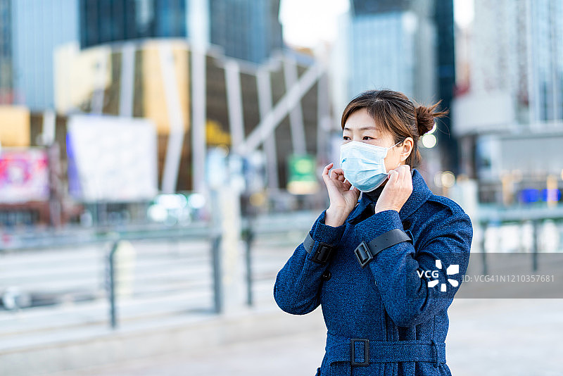 戴口罩的亚洲女人走在城市街道上图片素材