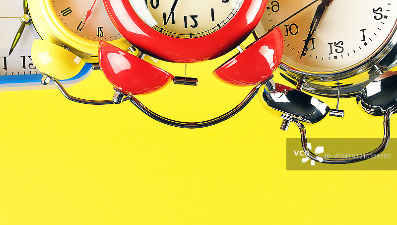 明亮黄色背景上复古风格的彩色闹钟合集banner图片素材