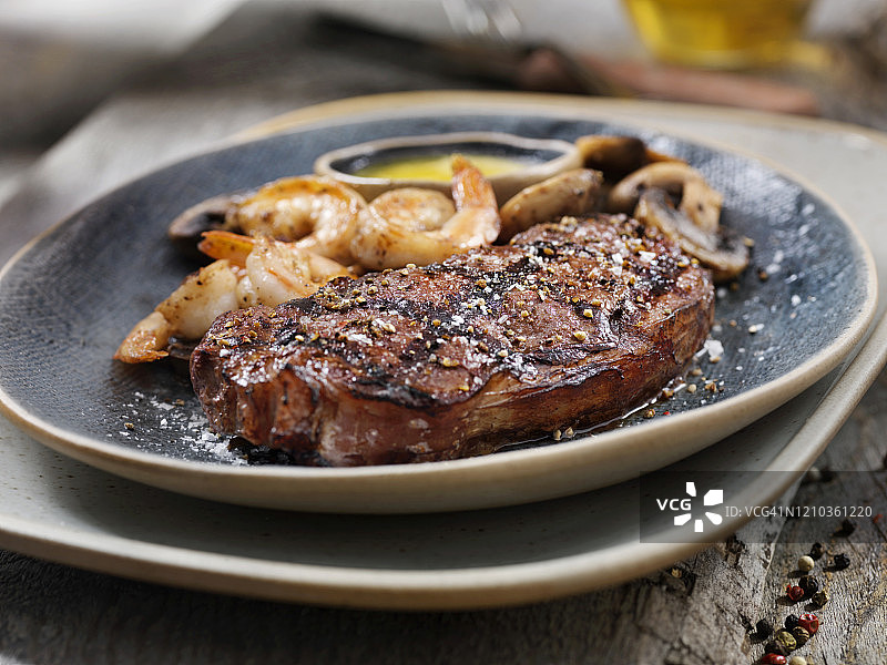 配有烤虾、蘑菇和香草蒜蓉黄油的五分熟西冷牛排中景图片素材
