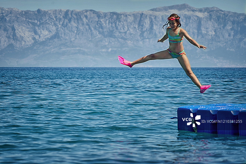 快乐的女孩在浮桥上跳入克罗地亚耶尔萨岛的海中图片素材