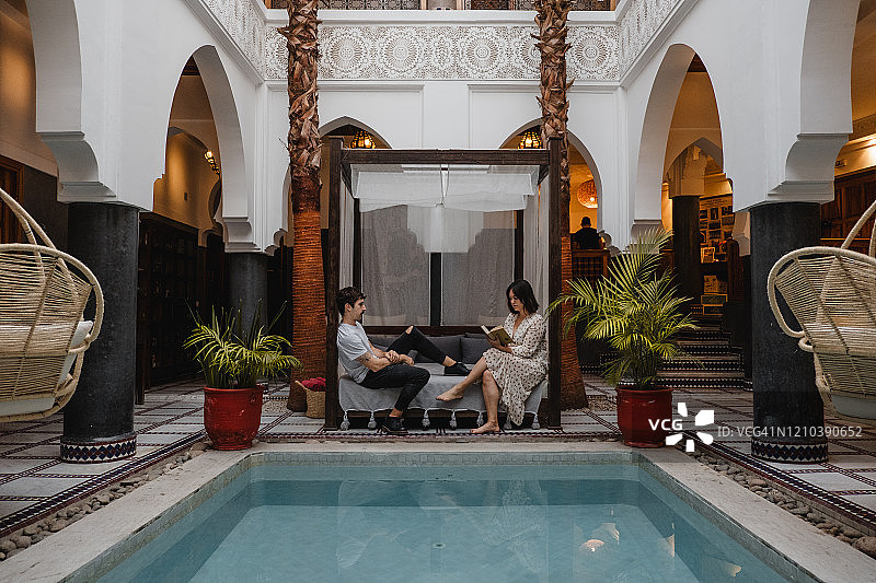 年轻夫妇在巴厘岛的床上休息，女子读书图片素材