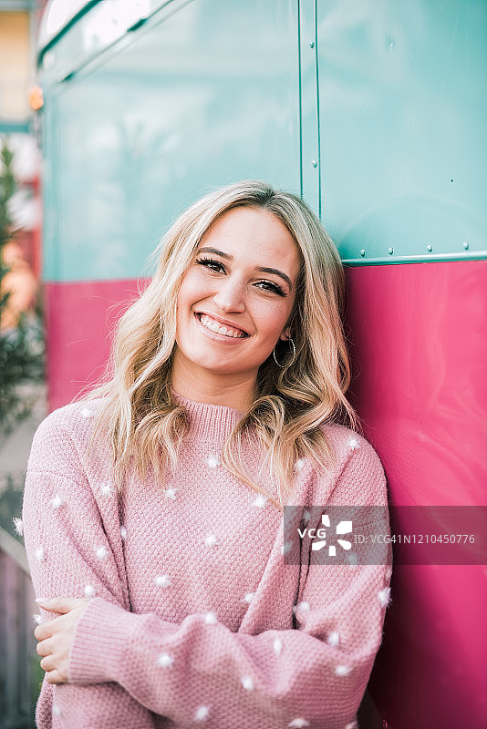 身穿粉色服装，倚靠在粉蓝色餐车旁的金发女孩图片素材