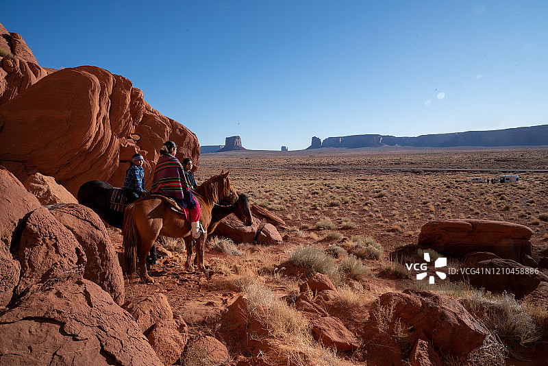 年轻纳瓦霍族青少年兄妹骑着马身后是岩层图片素材