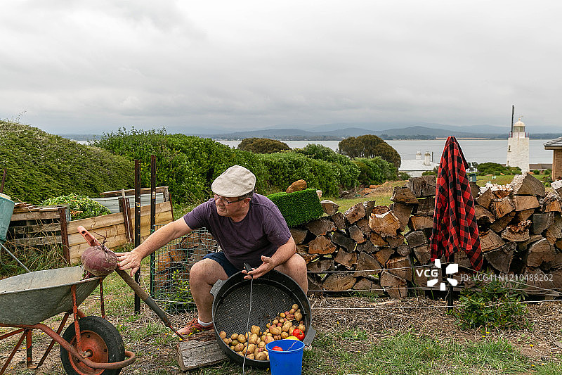 在夏季，年长的男人在塔斯马尼亚的河边和海边照料他的花园图片素材