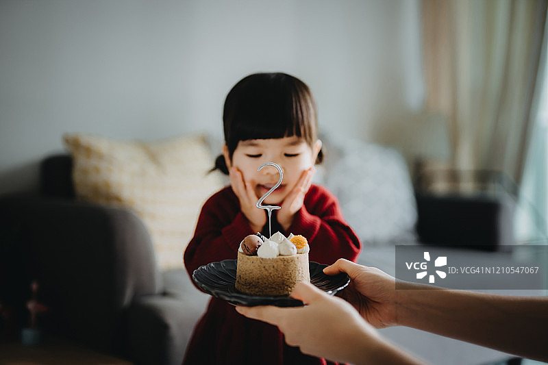 妈妈在家为两岁女儿准备生日蛋糕庆祝，小女孩感到惊喜和兴奋图片素材