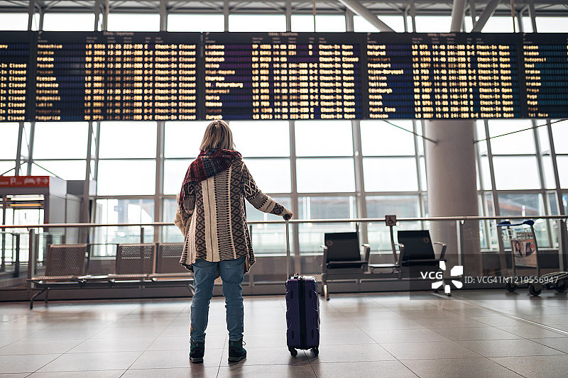 在机场阅读出发指示牌的女人图片素材
