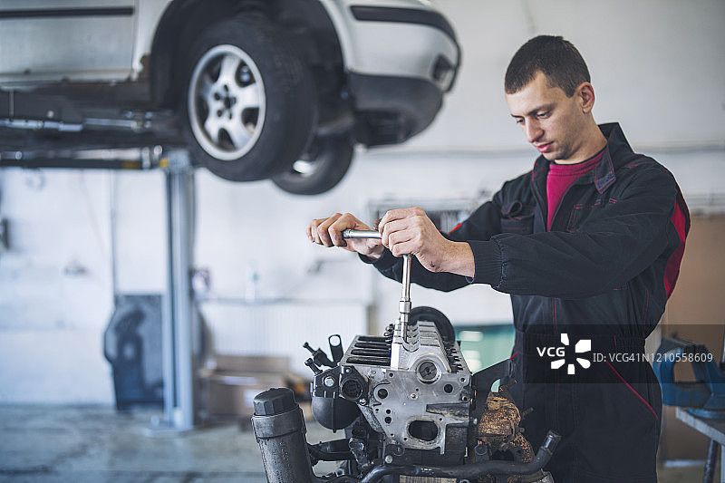 在车库修理汽车发动机的男修理工图片素材